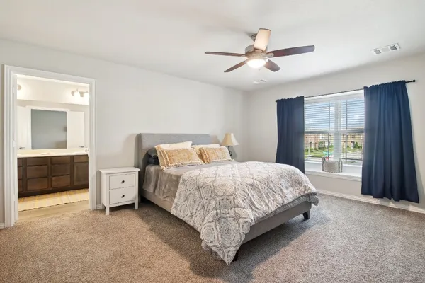 a bed sitting in a spacious bedroom next to a window and a bathroom