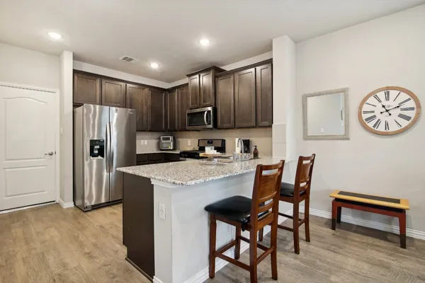 a view of kitchen with stainless steel appliances granite countertop dining table and chairs