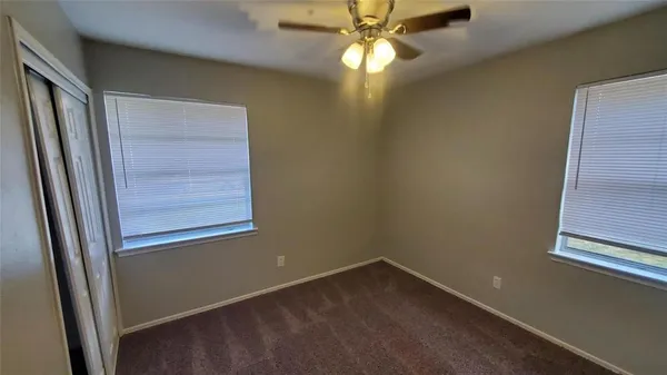 an empty room with windows and fan
