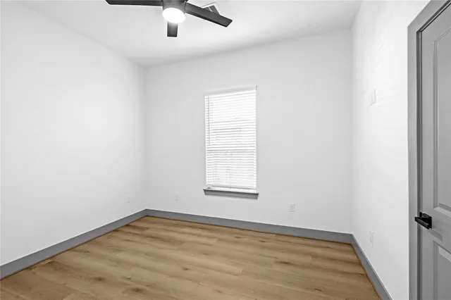 an empty room with a window and ceiling fan