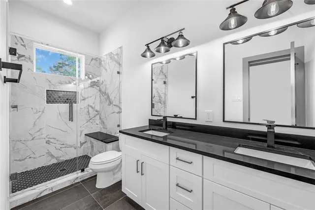 a bathroom with a granite countertop sink a toilet and a mirror