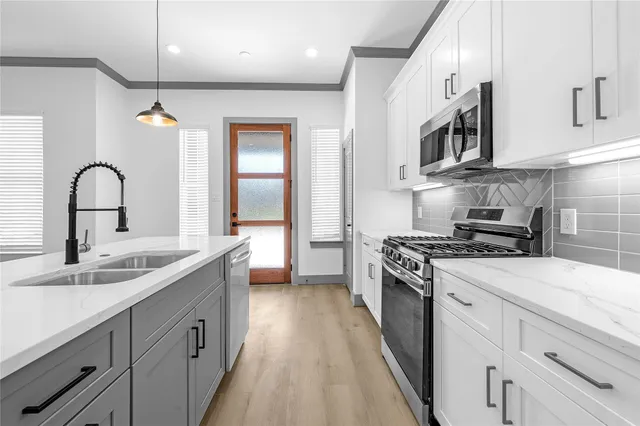 a kitchen with stainless steel appliances granite countertop a sink a stove and a refrigerator