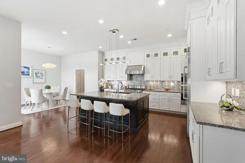 a kitchen with stainless steel appliances granite countertop a kitchen island hardwood floor sink stove dining table and chairs