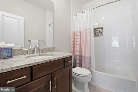 a bathroom with a granite countertop sink a toilet and shower