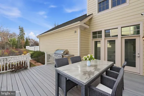 a roof deck with a dining table and chairs with wooden floor