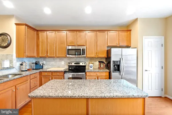 a kitchen with stainless steel appliances granite countertop a stove top oven a refrigerator a sink and dishwasher with wooden floor