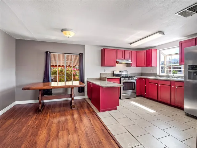 a kitchen with stainless steel appliances kitchen island granite countertop a stove a refrigerator and a living room view