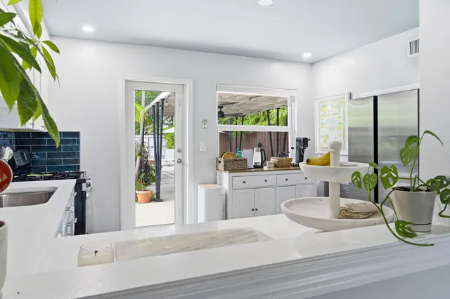 a kitchen with a stove a sink and a dining table with garden view