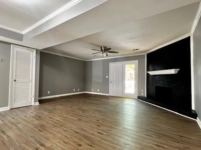 an empty room with wooden floor fireplace and windows