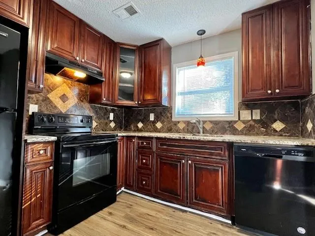 a kitchen with granite countertop wooden cabinets stainless steel appliances and a sink