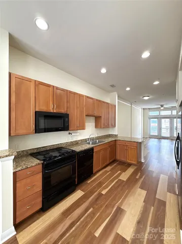 a large kitchen with stainless steel appliances wooden cabinets and a stove top oven