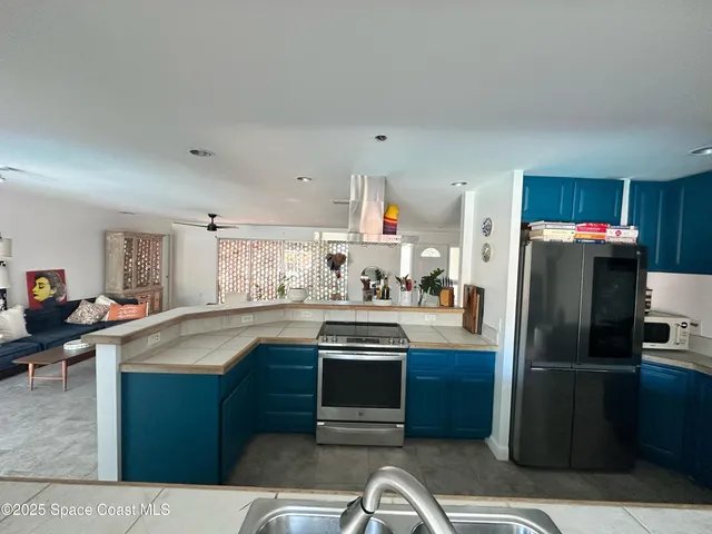 a kitchen with kitchen island a counter top space cabinets stainless steel appliances and a window