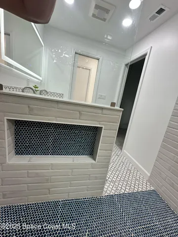 a bedroom with a bed a desk chair and windows