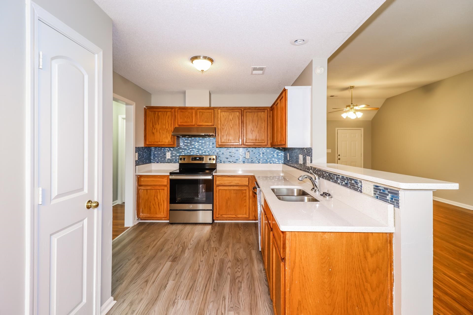 2415 North Forest Hill Irene Road Cordova, TN 38016 - Photo 6 of 16 Kitchen featuring light wood-style flooring, electric stove, tasteful backsplash, brown cabinetry, and light stone countertops