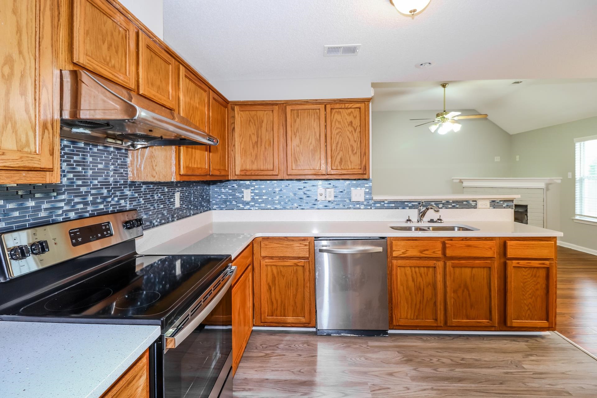 2415 North Forest Hill Irene Road Cordova, TN 38016 - Photo 7 of 16 Kitchen featuring stainless steel appliances, a peninsula, decorative backsplash, light wood-type flooring, and under cabinet range hood