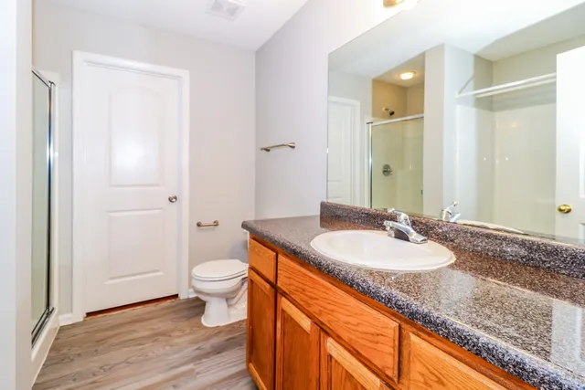 an empty room with wooden floor chandelier fan and windows