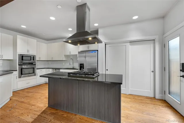 a kitchen with stainless steel appliances granite countertop a sink a stove and a wooden floors