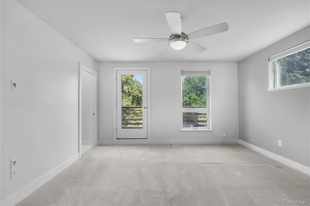 an empty room with windows and ceiling fan