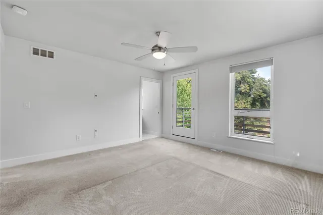 an empty room with a window and a ceiling fan