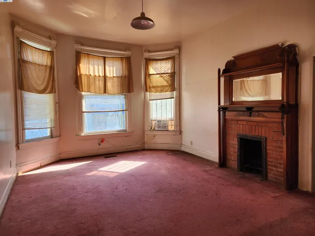 an empty room with windows cabinet and fireplace