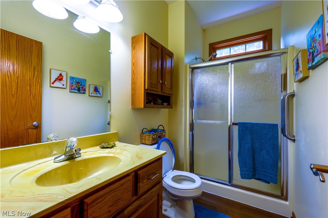 5675 Post Boy Road Southwest Newcomerstown, OH 43832 - Photo 16 of 26 Bathroom with walk in shower, hardwood / wood-style flooring, vanity, and toilet