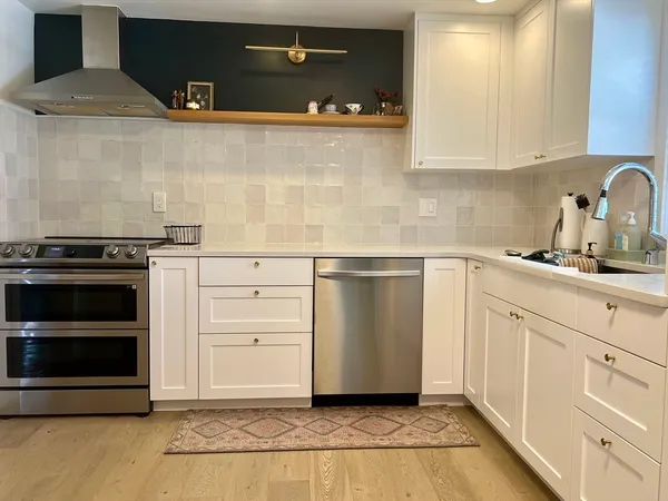 a kitchen with white cabinets and appliances