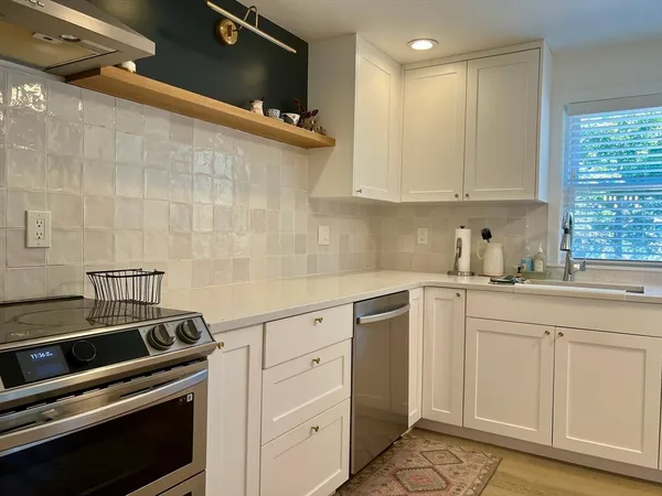 a kitchen with white cabinets and appliances