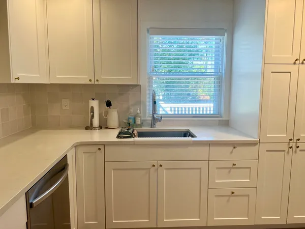 a kitchen with white cabinets and sink