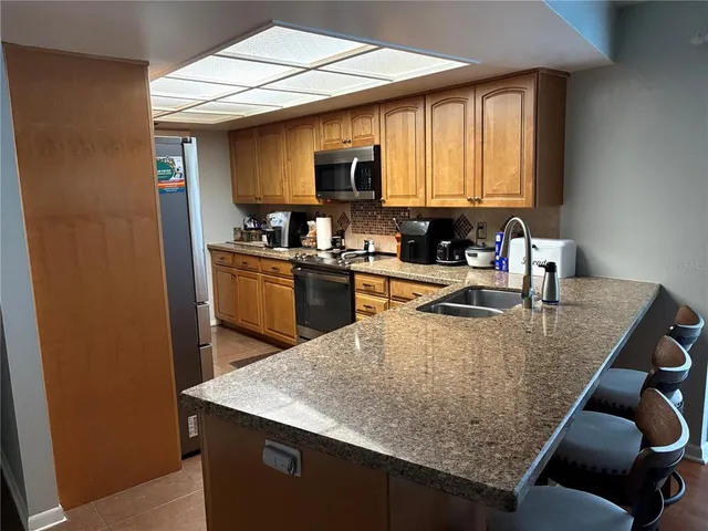 a kitchen with granite countertop a sink a counter top space and stainless steel appliances