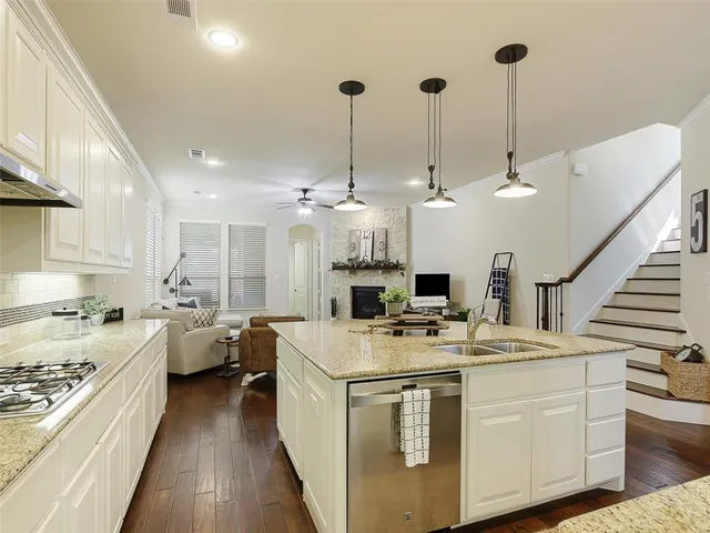 a kitchen with stainless steel appliances kitchen island a stove a sink dishwasher a refrigerator white cabinets with wooden floor