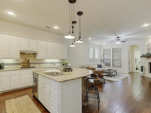 a kitchen with a sink dishwasher a stove a dining table and chairs with wooden floor