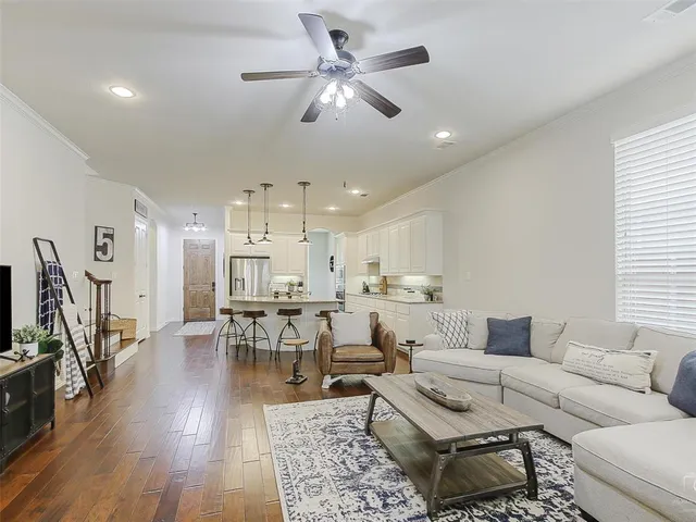 a living room with furniture kitchen view and a wooden floor