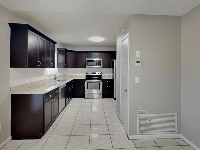 a large kitchen with stainless steel appliances kitchen island granite countertop a refrigerator and a sink