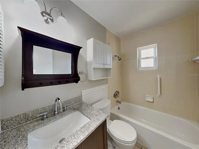 a bathroom with a granite countertop toilet sink and mirror