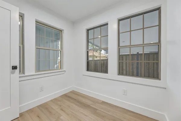 an empty room with wooden floor and windows