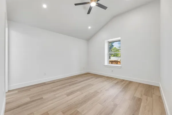 an empty room with windows and ceiling fan