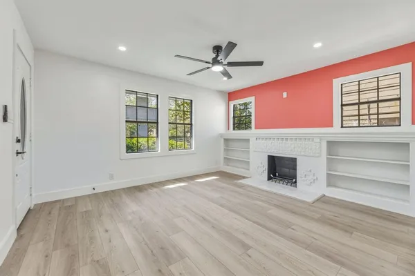 an empty room with windows fireplace and wooden floor