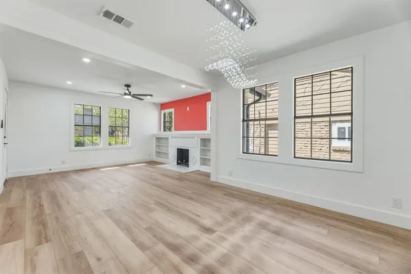 a view of an empty room with a window and chandelier fan