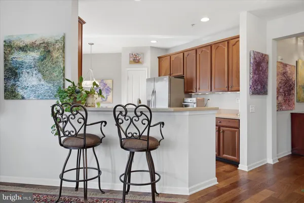 a kitchen with stainless steel appliances kitchen island a table chairs in it and wooden floor