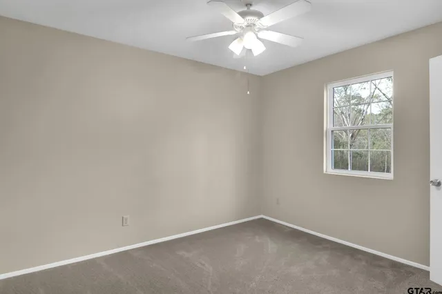 an empty room with a window and a fan
