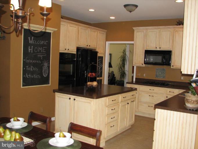 5910 Sunlight Mountain Road Spotsylvania, VA 22553 - Photo 18 of 30 a kitchen with stainless steel appliances a stove a sink a refrigerator a microwave a refrigerator and white cabinets with wooden floor