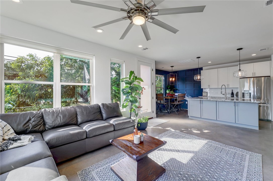 a living room with furniture and a large window with kitchen view