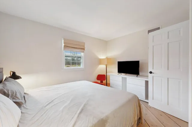 a bedroom with a bed and a flat tv screen on wall