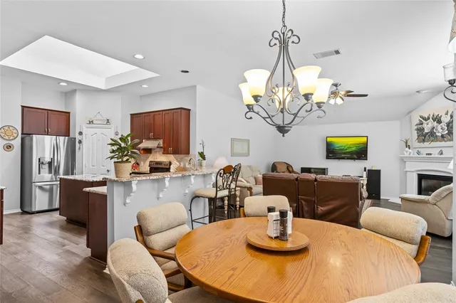 a kitchen with stainless steel appliances granite countertop a stove a refrigerator a sink a dining table and chairs with wooden floor