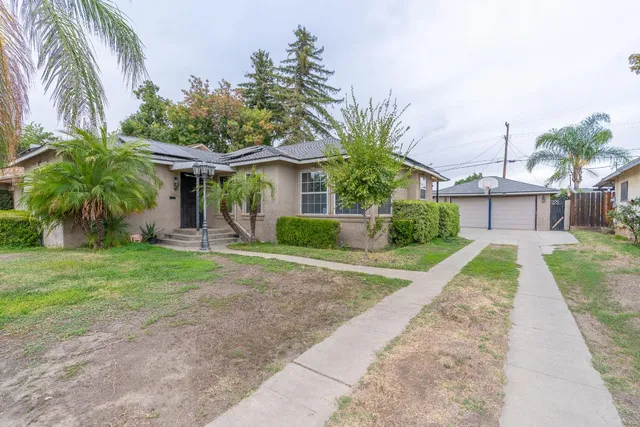 front view of a house with a yard and palm trees