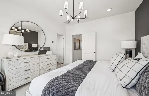 a bedroom with a bed a chandelier and dresser