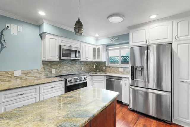 a kitchen with stainless steel appliances granite countertop a refrigerator a stove a sink dishwasher a oven with white cabinets and wooden floor