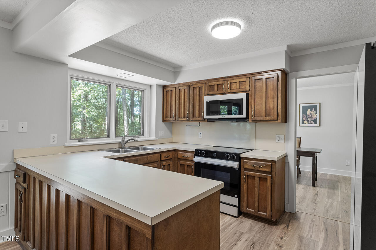 705 Lanham Place Raleigh, NC 27615 - Photo 12 of 53 a kitchen that has a sink a microwave oven a stove and white countertops with wooden floor