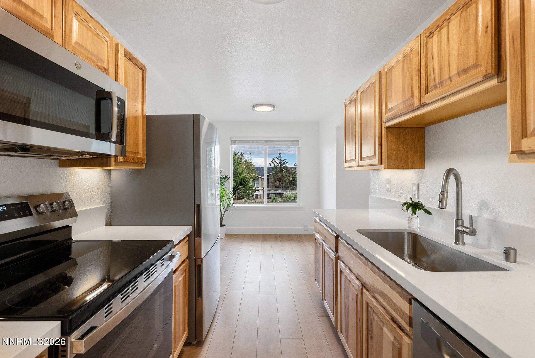 3935 Clear Acre Lane, Unit 211 Reno, NV 89512 - Photo 4 of 25 a kitchen with stainless steel appliances a sink a stove and a microwave