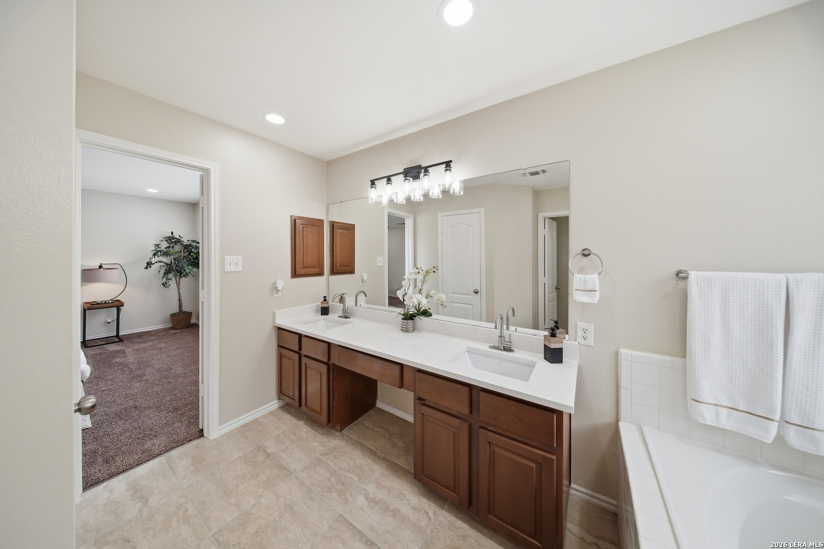 5607 Spring Quail San Antonio, TX 78247 - Photo 13 of 25 a spacious bathroom with a double vanity sink a mirror and a shower